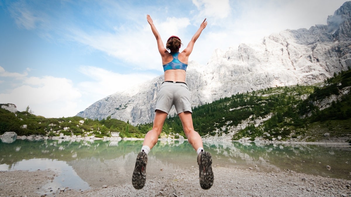 woman jumping wearing blue sports bra and grey shorts